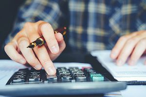 A person calculating cost to develop custom software for clients