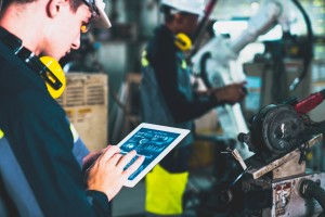 two factory workers using data monitoring software to start an orde