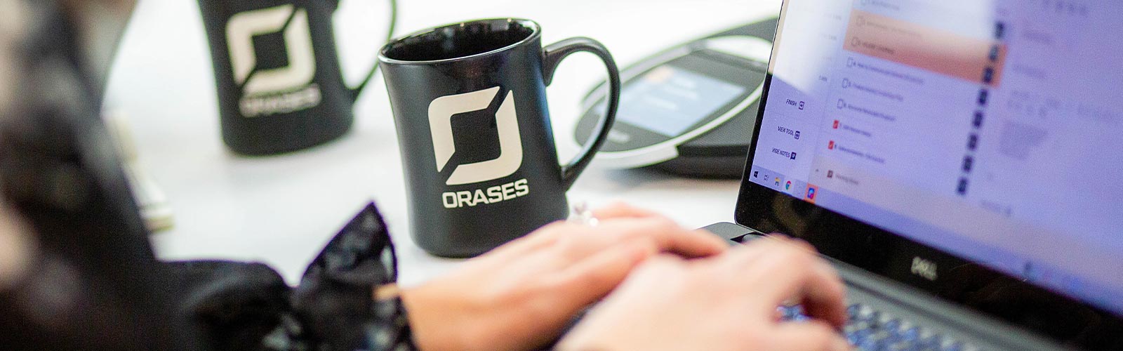 woman typing on computer next to orases mug