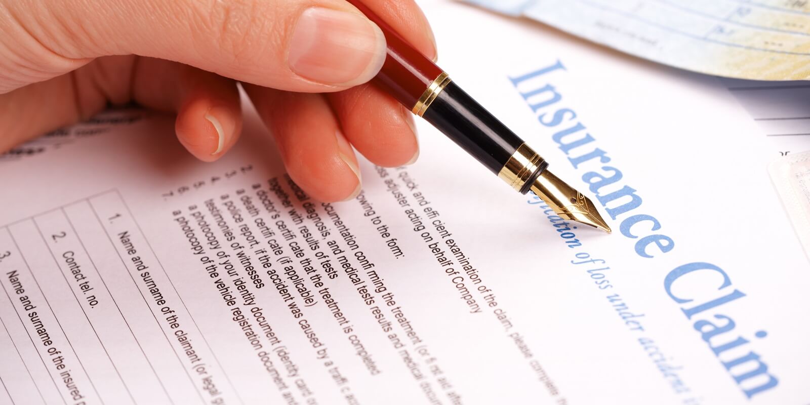 hand filling in insurance claim form