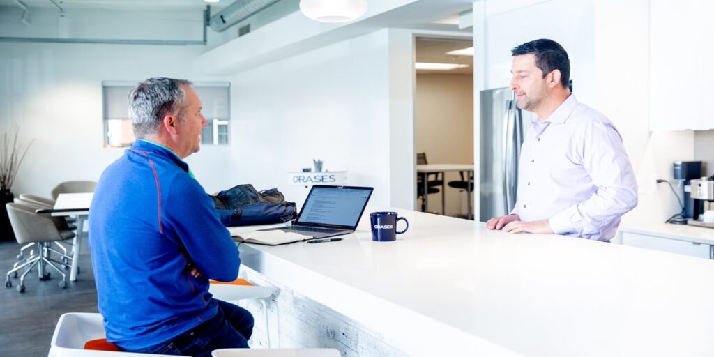 collegues over discusssion while working on laptop
