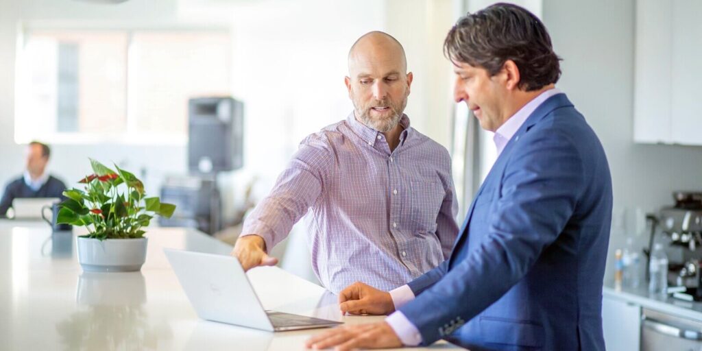 men are engaged in a discussion in an office setting