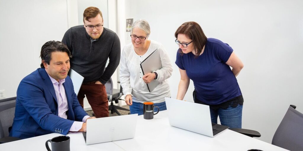 man showing project to details to the collegues in a laptop