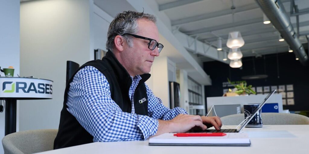 man working on a laptop with notepad and pen placed nearby