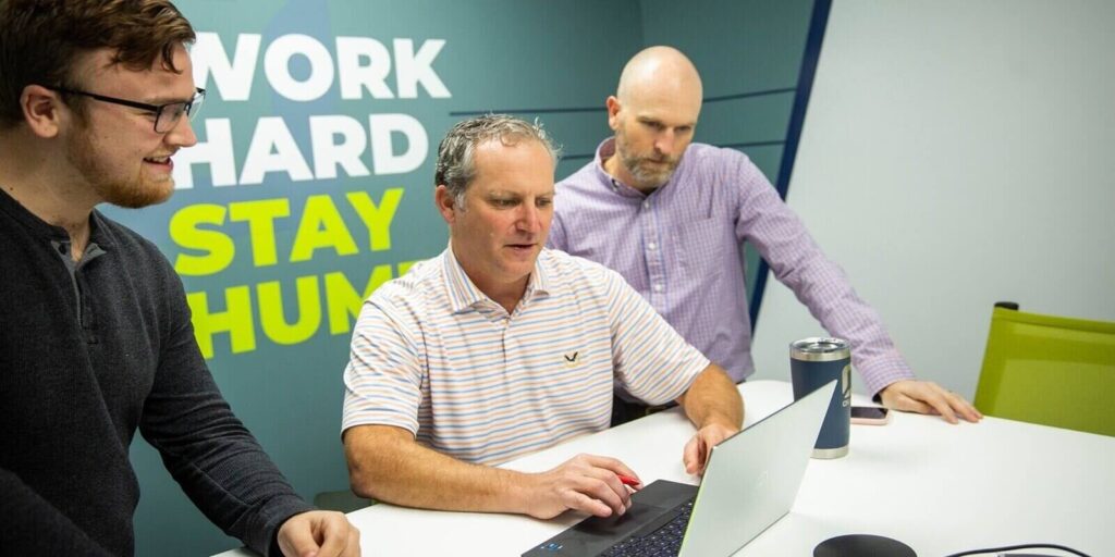 three colleagues collaborating on a project, discussing ideas and working together in a modern office setting