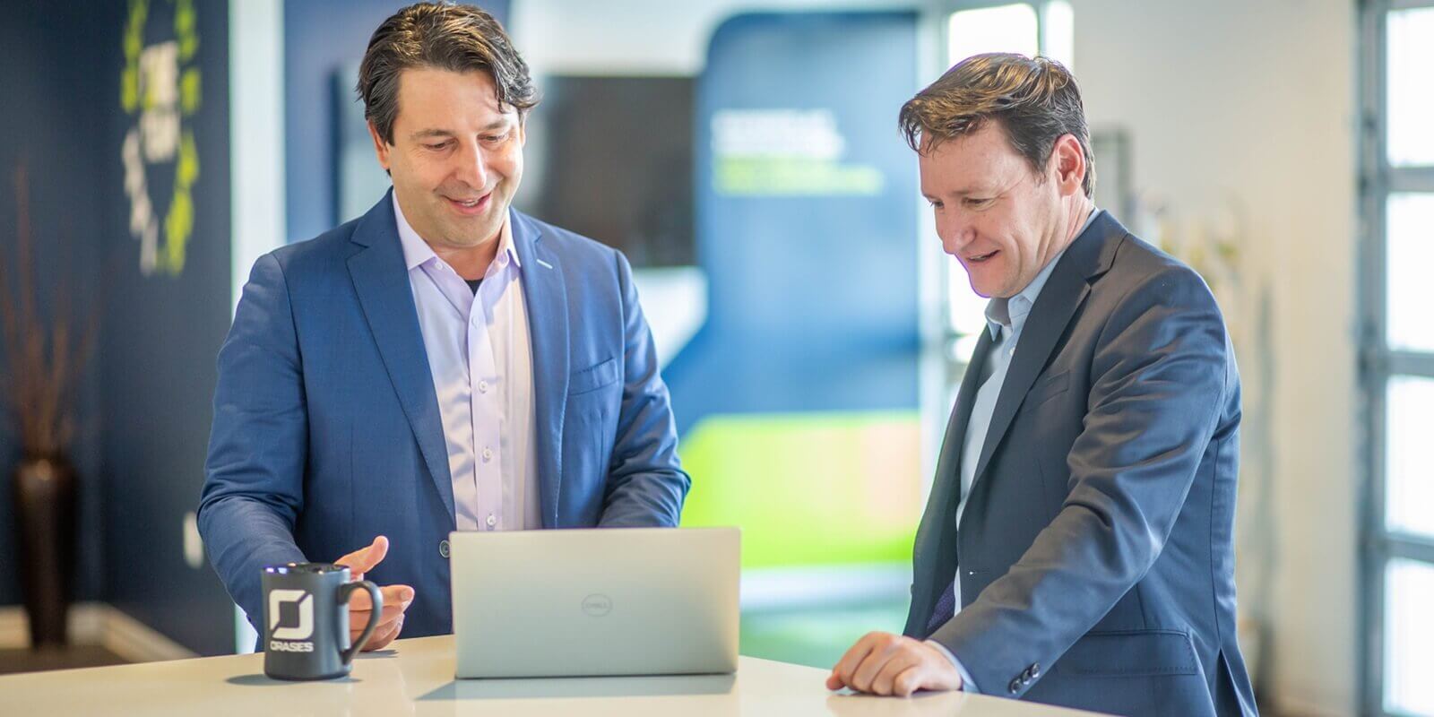 two male employees discussing a presentation on a laptop