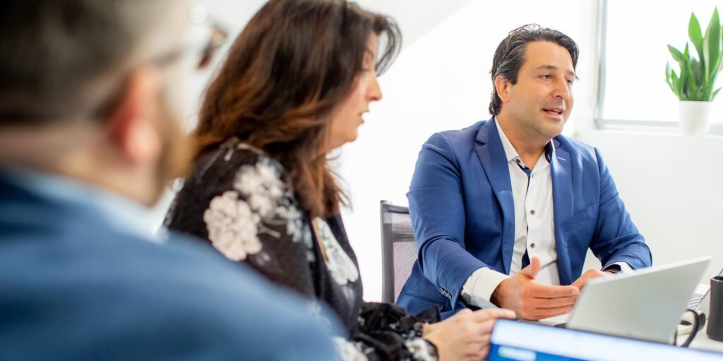 business professionals engaged in a discussion during a meeting, with one person actively presenting while others listen and take notes